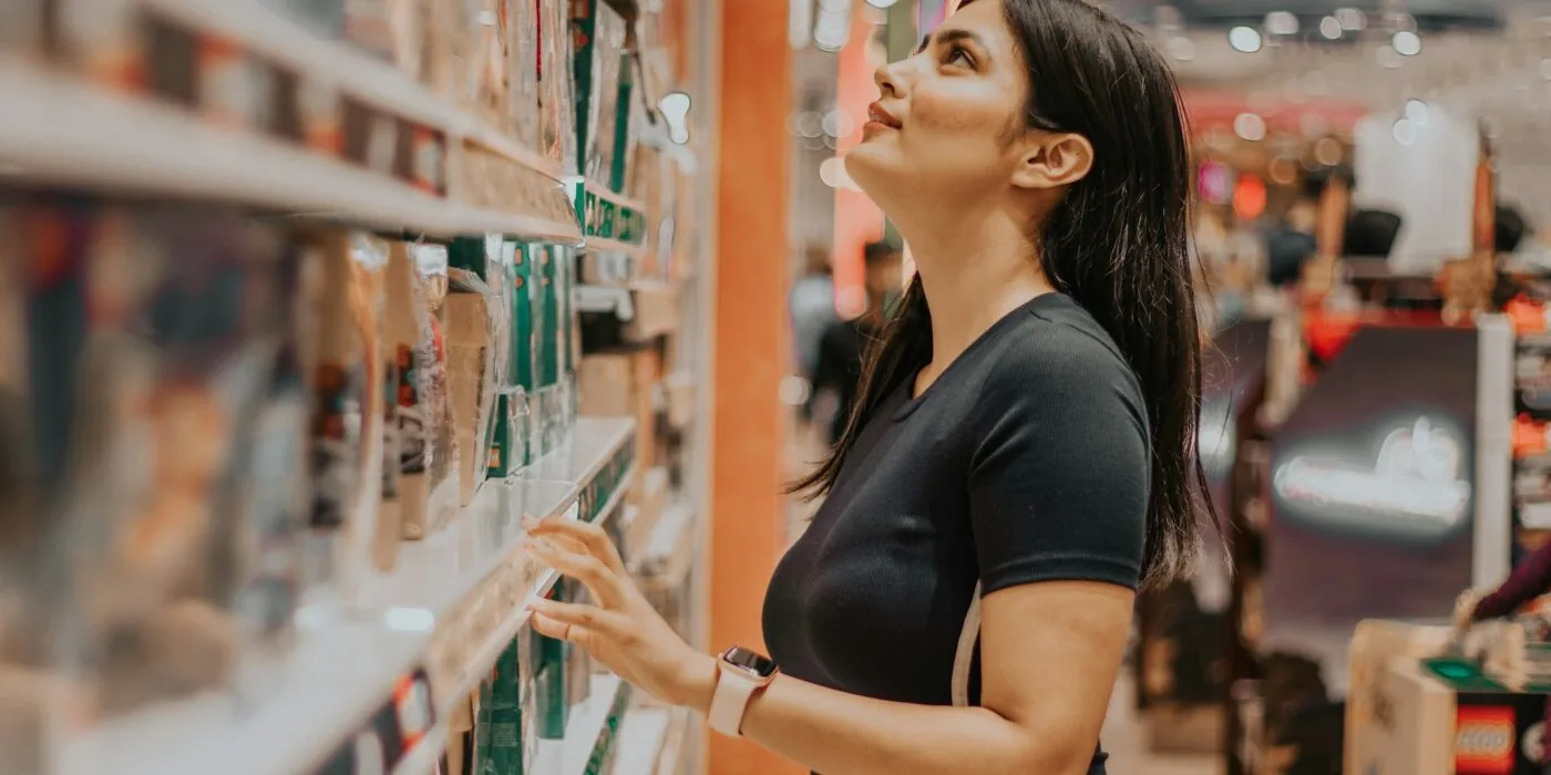 Customer examining electronics with discount signs in modern tech store