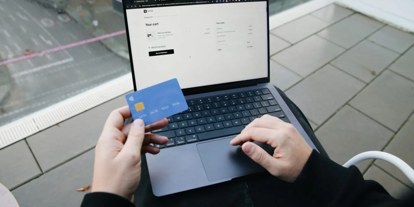 Person making online purchase on laptop with credit card, representing digital payment and checkout process