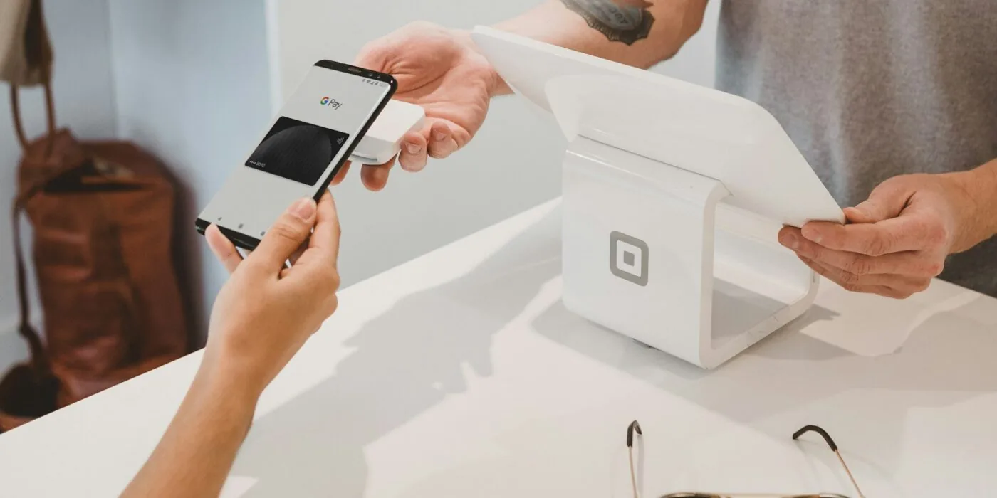 Person using smartphone to scan coupon code at retail store checkout counter