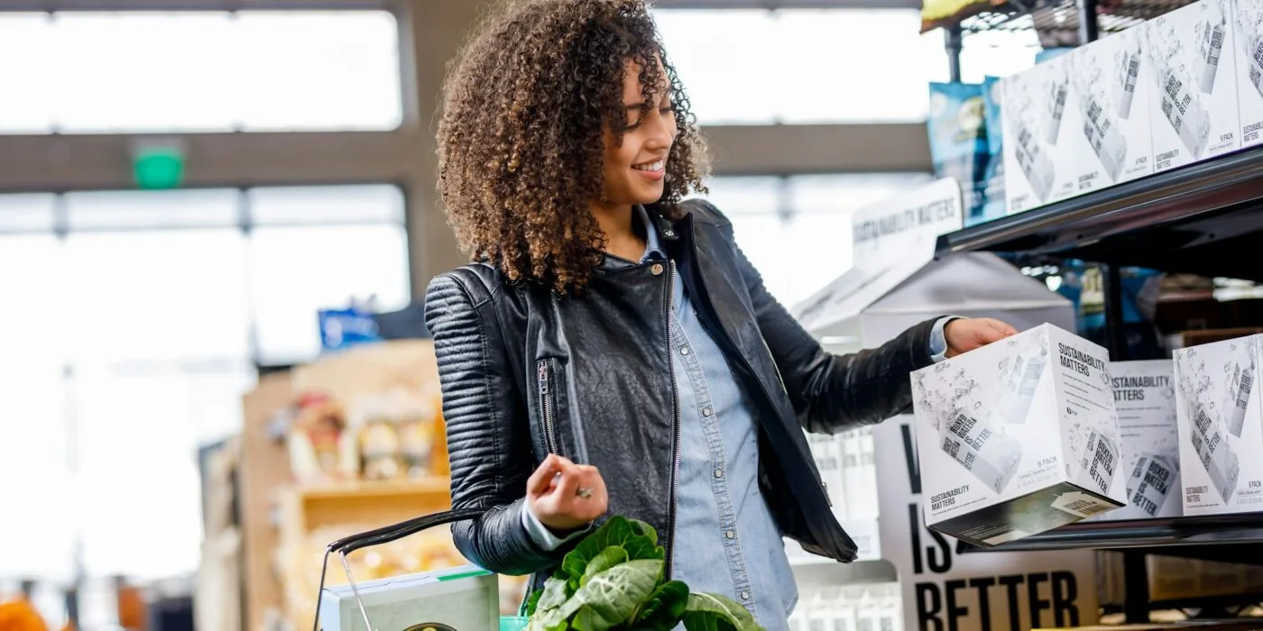 Shopper reviewing coupons and receipt at grocery store checkout in natural lighting