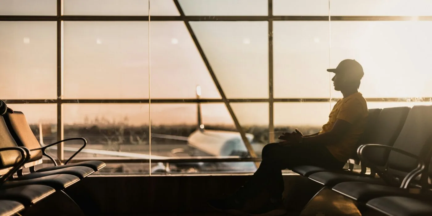 Traveler comparing airline codes and hotel reservations on laptop at airport gate